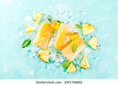 Homemade Pineapple Popsicles on Ice with fresh Pineapple slices and mint, on light blue background copy space top view - Powered by Shutterstock