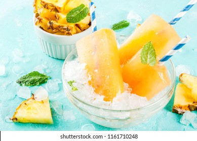 Homemade Pineapple Popsicles on Ice Cubes with fresh Pineapple slices and mint, on light blue background copy space - Powered by Shutterstock