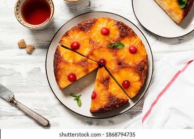 Homemade pineapple upside down pie with candied cranberry . Tropical dessert on white wooden background . Top view.