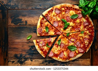 Homemade pizza Hawaiian with ham and pineapple on a dark wooden background.Top view with copy space. - Powered by Shutterstock