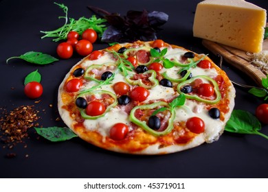 Homemade Pizza With Salami, Black Olives And Basil On A Black Background.