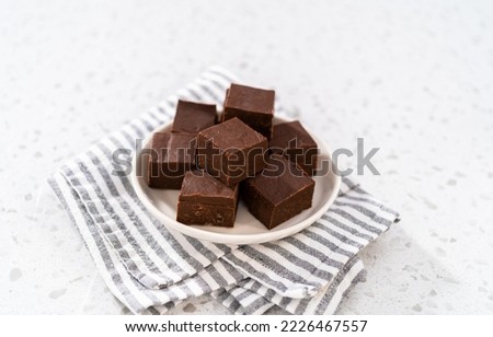 Homemade plain fudge pieces on a white ceramic plate.