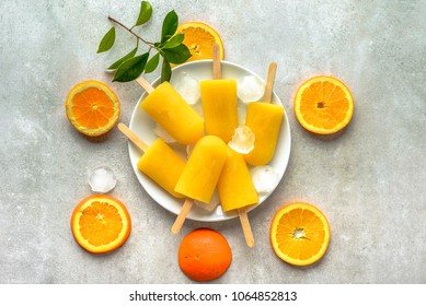 Homemade popsicles with orange juice, ice lollies on sticks, top view flat lay
