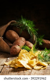 Homemade Potato Chips With Salt And Dill, Raw Potatoes In A Bag On A Old Wooden Dark Background, Selective Focus