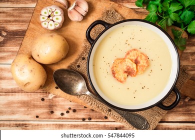 hausgemachte Kartoffelcremesuppe mit Kartoffelchips auf Holztisch