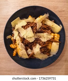 Homemade Poutine Dish Made With Curly Fries, Shredded Slow Cooked Beef And Cheese Curds Served In A Blue Bowl. Cooking At Home Concept. Top View, Flat Lay, From Above.