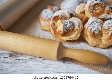 Homemade puff pastry with sugar powder and rolling pin on wooden background