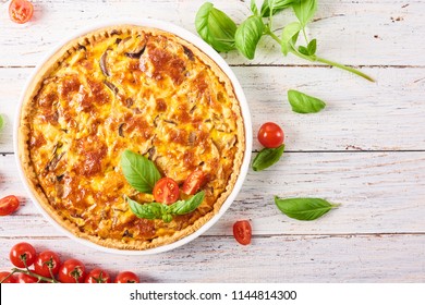 Homemade quiche lorraine with chicken, mushrooms and cheese on white wooden background. French cuisine
