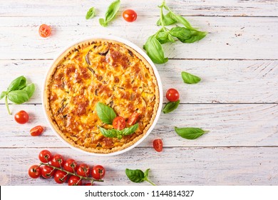 Homemade quiche lorraine with chicken, mushrooms and cheese on white wooden background. French cuisine