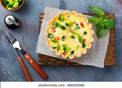 Homemade quiche tart with red fish salmon, broccoli, basil, seasonings and cheese on a gray stone background. Selective focus.Top view.
