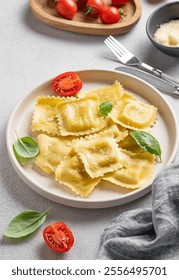 Homemade ravioli pasta with cheese, tomatoes and basil in a plate on a light background with fork and napkin. Traditional Italian food concept.