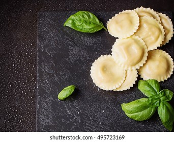 Homemade ravioli, penne and fusilli pasta with fresh basil and riccotta cheese and wooden roller over the stone slate board. Top View