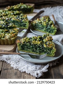 Homemade rectangular Spinach quiche made with spinach green dough, with mozzarella cheese, buttermilk cream and black sesame seeds, garnished with leaves cut from the same dough
over  wooden surface - Shutterstock ID 2129750423