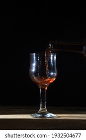 Homemade red wine is poured into a glass on a dark background. Glass of red wine on a black background. Alcoholic beverage