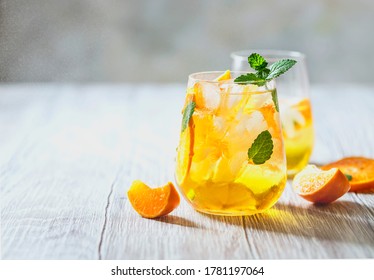 Homemade refreshing iced tea with orange and lemon on a wooden rustic table. Summer refreshing drink concept. Selective focus