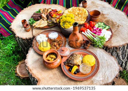 Homemade Romanian Food with grilled meat, polenta and vegetables Platter on camping. Romantic traditional moldavian food outside on the wood table.