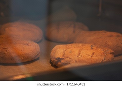 Homemade Round Brown Rye Fletbread Baking In Electric Oven. Production Oven At The Bakery. Fresh And Crunchy Home Made Bread. View Through Glass Oven Door. Selective Focus