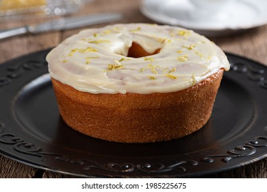 Homemade Round Lemon Cake With Topping And Lemon Zest On A Plate On A Rustic Wooden Table