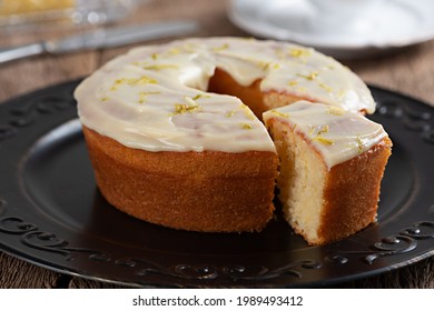 Homemade Round Lemon Cake With Topping And Lemon Zest On A Plate On A Rustic Wooden Table With On Slice