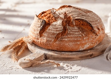 Homemade round loaf bread on wooden cutting board. Bread in countryside. - Powered by Shutterstock