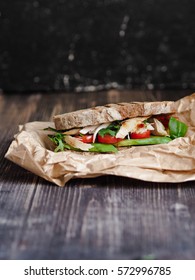 Homemade Sandwiches With Chicken, Tomato, Avocado And Arugula On Grilled Toast On The Paper Bag On A Dark Background

