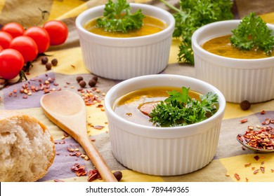 Homemade sausage soup with parsley in white ramekin bowls