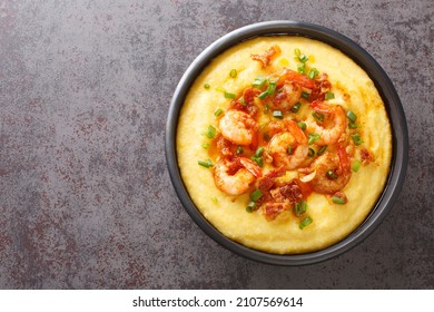 Homemade shrimp and grits with smoked bacon, onions and cheese in a black bowl on a dark concrete background. American cuisine. Horizontal top view from above - Shutterstock ID 2107569614