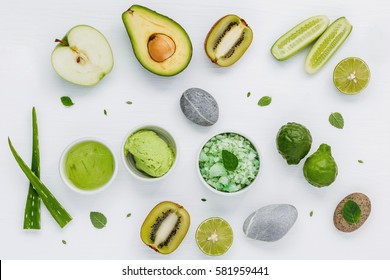 Homemade skin care and body scrubs with green natural ingredients aloe vera ,lime,cucumber ,aromatic salt ,green apple,mint ,rosemary ,kiwi and sage set up on white wooden background with flat lay.