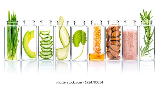 Homemade skin care with natural ingredients wheat grass ,avocado ,aloe vera ,cucumber ,himalayan salt  ,honeycomb ,almonds, centella asiatica and rosemary  in glass bottles isolate on white background - Shutterstock ID 1924780334