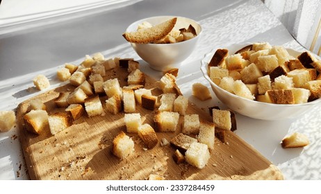 Homemade slices of diced dry white rye bread on cutting board and white plate. Crackers for food, healthy eating on table in sunny day. Top view - Powered by Shutterstock