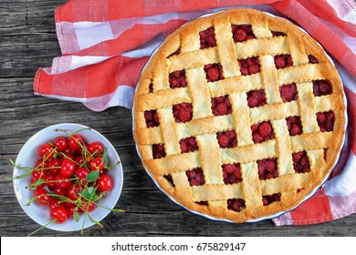 homemade sour cherry pie with pretty lattice top decorated with fresh ripe cherry in baking dish on dark wooden table with kitchen towel and bowl with ripe cherries, classic recipe, view from above