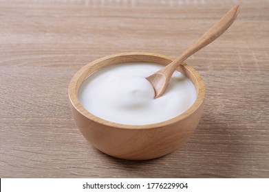 Homemade sour cream yogurt in wooden bowl on table.