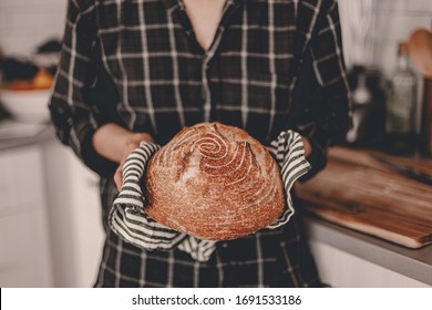Homemade sourdough bread. Bright white kitchen. Bread on cutting board. Kitchen utensils. Craft authentic bread. Home cooking. Food preparation. Coronavirus covid-19 stay home isolation quarantine.