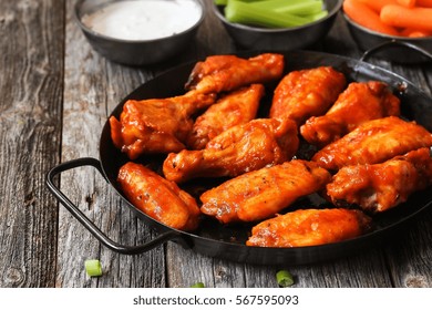 Homemade Spicy Buffalo Chicken Wings Served With Blue Cheese Dip Celery Sticks And Baby Carrots On Rustic Wooden Background / Game Day Platter