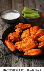 Homemade Spicy Buffalo Chicken Wings Served With Blue Cheese Dip Celery Sticks And Baby Carrots On Rustic Wooden Background / Game Day Platter