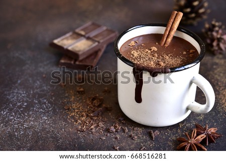 Homemade spicy hot chocolate with cinnamon in enamel mug on a slate,stone or concrete background.