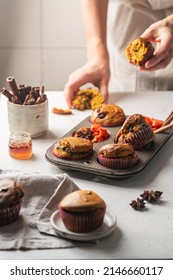 Homemade Spicy Pumpkin Muffins Or Cupcakes With Chocolate On A Metal Rack With Woman Hands In The Background. Autumn Dessert. Selective Focus