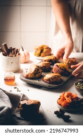 Homemade Spicy Pumpkin Muffins Or Cupcakes With Chocolate On A Metal Rack With Woman Hands In The Background. Autumn Dessert. Selective Focus