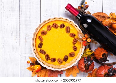 Homemade Spicy Pumpkin Pie With Cinnamon And Pecan Nuts And Bottle Of Red Wine On Wooden Rustic Table. Traditional Fall Sweet Dessert For Thanksgiving Day