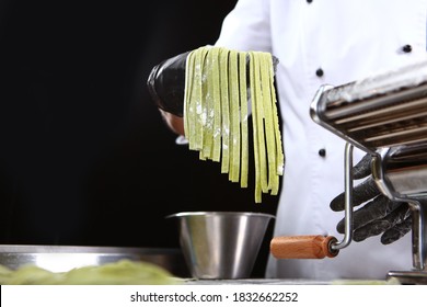 Homemade spinach paste. Machine for making pasta. Unrecognizable person. Photo on a black background. Copy space.