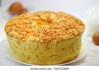 Homemade Sponge Cake Or Chiffon Cake With Cheese Flavor On White Plate. Soft And Delicious Cake With Ingredients; Eggs, Flour, Milk, Cheese On Table. Bakery Concept For Background Or Wallpaper.