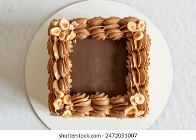 Homemade sponge cake in the shape of a square, top view. Cooking. Pastry masterpieces.   Cake decorated with buttercream and nuts, on gray background. Flat Lay.   