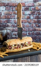 A Homemade Steak And Blue Cheese Hoagie With A Sharp Knife Standing Up.