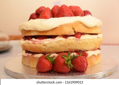 Homemade Strawberry And Cream Sponge Layer Cake. Juicy Red Strawberries Triple Layer Cake On A Table Ready For A Birthday Party