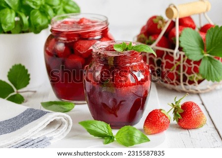 Homemade strawberry jam with basil and whole berries in glass jars. selective focus