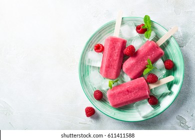 Ghiaccioli alla fragola fatti in casa su piatto verde con ghiaccio, fragole e menta. Concetto di cibo estivo sano con spazio copia.