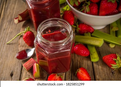 hausgemachte Erdbeermarmelade mit Marmelade oder Sauce, mit frischem Rhubarb und Erdbeeren und Gewürzen, rustikaler Holzhintergrund, Kopienraum 