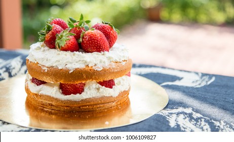 Homemade strawberry shortcake on gold plate with outdoor blurry background