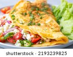 Homemade stuffed omelet on a plate. Egg omelet stuffed with fresh tomatoes, cheese and green parsley. Healthy vegetarian breakfast recipe.