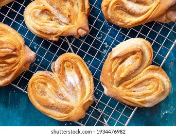 Homemade sugar buns on a cooling rack with sugar for sprinkling. Palmiers, elephant ear, puff pastry cookie. - Powered by Shutterstock